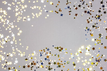 Holiday Festive background. gold and silver star confetti glitter scattered on grey background....