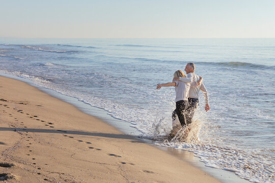 Couple splashing water on each other at beach