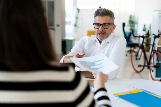 Colleague passing progress report to businessman at office