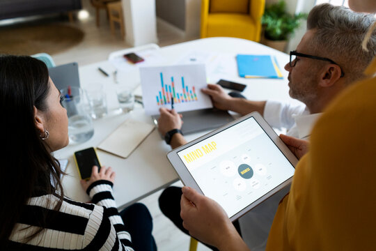 Businessman examining graph report with colleagues at office