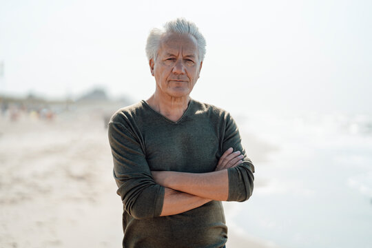Senior man with arms crossed at beach
