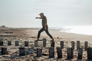 Carefree senior man walking on wooden posts at beach