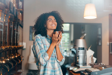 Happy owner with eyes closed smelling roasted coffee in cup at store