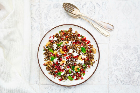 Studio shot of plate of quinoa salad with feta cheese, pomegranate seeds and cashews