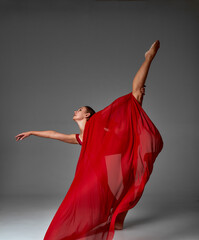 Ballerina Jumping in Pointe Shoes with Flying Red Cloth, Modern Ballet Dance, Isolated Gray Background