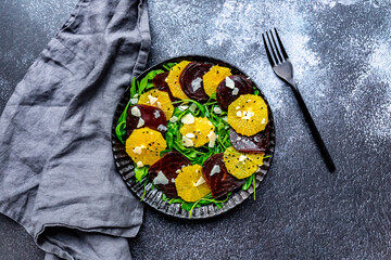 Studio shot of plate of vegetarian salad with orange and beetroot slices, arugula, Parmesan and black sesame seeds