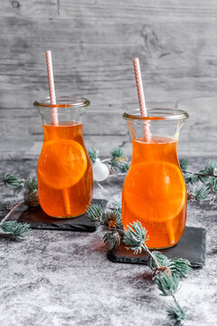 Studio shot of twigs and two bottles of hot Aperol with orange slices