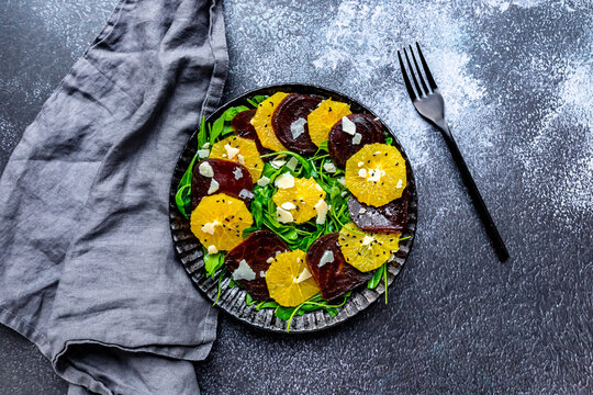Studio shot of plate of vegetarian salad with orange and beetroot slices, arugula, Parmesan and black sesame seeds