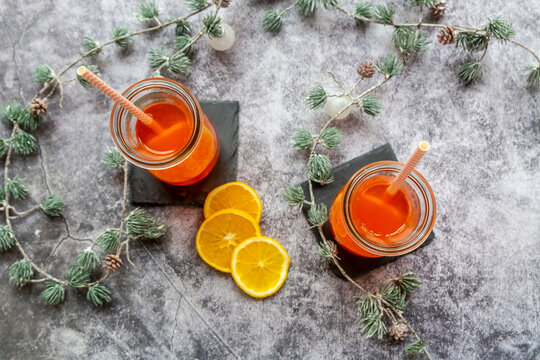 Studio shot of twigs and two bottles of hot Aperol with orange slices