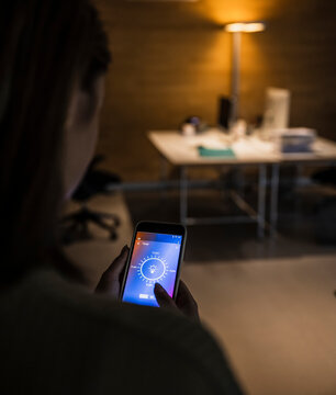 Woman using light bulb icon mobile phone screen at home