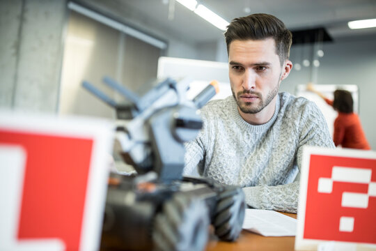 Technician looking at remote controlled combat tank in workshop