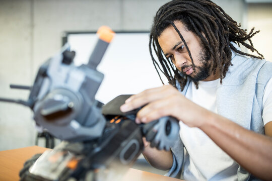 Technician with braided hair working with combat tank at workshop