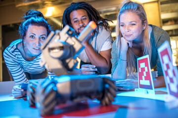 Young technician with colleagues looking at automated robotic combat tank at workshop