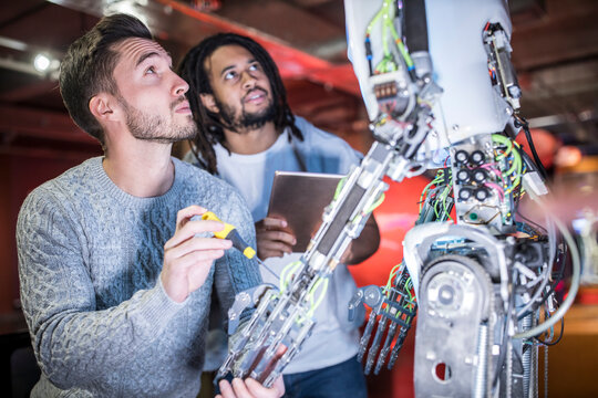 Engineers examining robotic arm at workshop