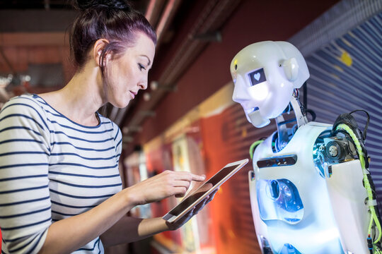 Technician programming human robot through tablet PC at workshop