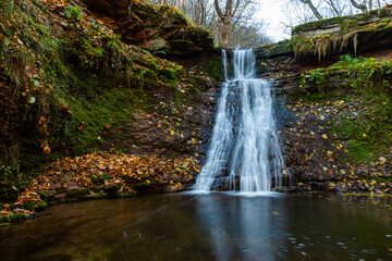 Obraz premium Tranquil waterfall scenery in the middle of autumn forest