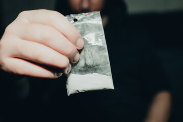 Criminal holding plastic bag with drug.Man holding transparent plastic zip lock bag with drugs. Concept-criminal with drugs.closeup,selective focus,toned.