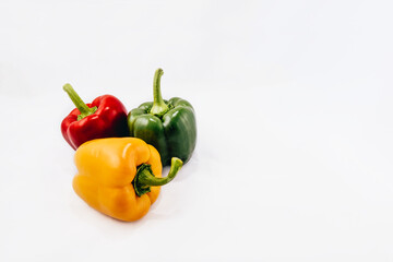 Three fresh whole bell peppers isolated on white background. Green, red and yellow peppers.