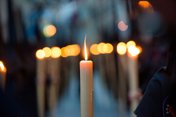 selective focus detail of a lighted candle carried by a penitent, during a Holy Week procession in...