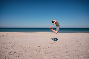 Handsome guy jumping on the background of the ocean. Active rest by the sea.