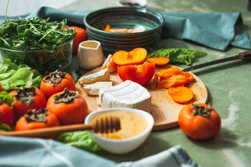 Ingredients and the process of making a vitamin winter salad with persimmons, tangerines and...