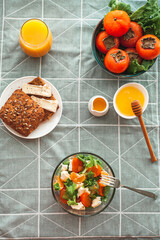 Vegan breakfast or lunch. Light sweet and sour salad with persimmon, tangerines and cheese. Winter vitamin salad on white table with a green napkin Diet food. Selective focus 