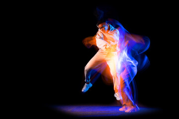Sportive young girl in white costume dancing hip-hop dance isolated on dark background at dance...