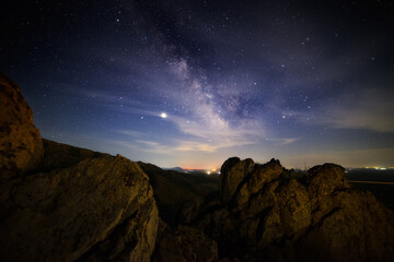 Milky Way shot on top of a small mountain with city lights in the distant background