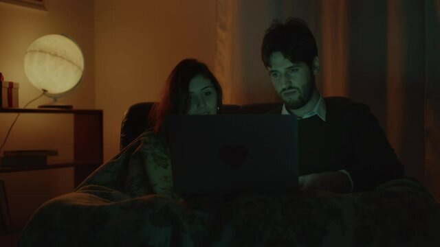Coppia guarda film su computer portatile per san Valentino in casa