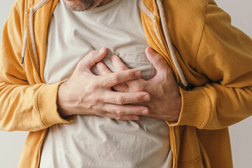 Aching heart and heart attack, adult male with painful grimace pressing the upper abdomen