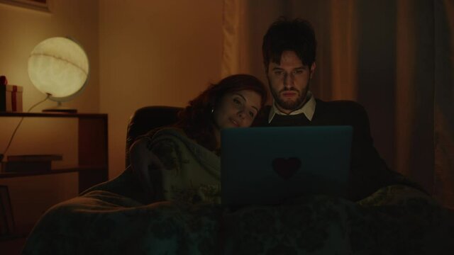Coppia guarda film su computer portatile per san Valentino in casa