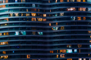 Fototapeta na wymiar Glass facade of modern city high rise, buildings show lighting using by human activity, energy usage at night time. Glowing windows of skyscrapers at night.