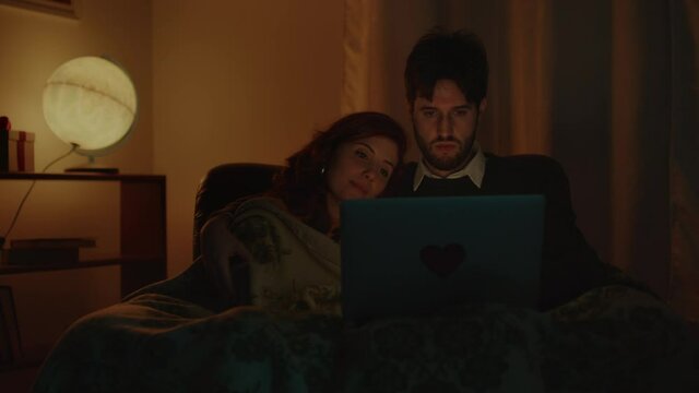 Coppia guarda film su computer portatile per san Valentino in casa