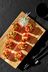 Sushi roll in mamenori with chopped baked shrimp, tomato, scallions on wooden board
