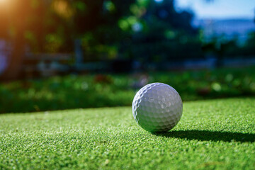 Golf ball on fairway of beautiful golf course at summer sunset.