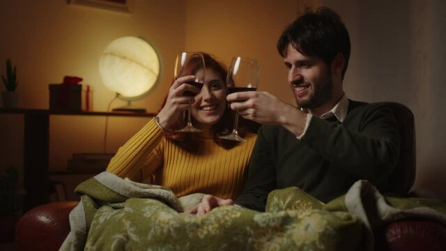Coppia beve dai calici di vino sul divano in casa