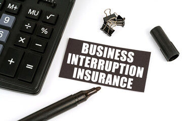 On a white table there is a calculator, a marker and a black plate with the inscription Business...