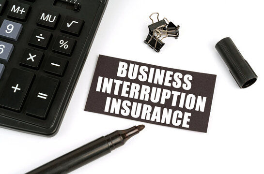 On a white table there is a calculator, a marker and a black plate with the inscription Business Interruption Insurance