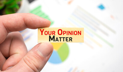 Cropped view of hands holding wooden cube with Your Opinion Matter lettering on work table. Top view
