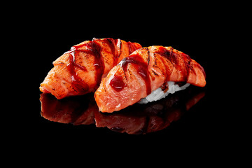 Closeup of nigiri sushi with seared salmon and unagi sauce isolated on black background