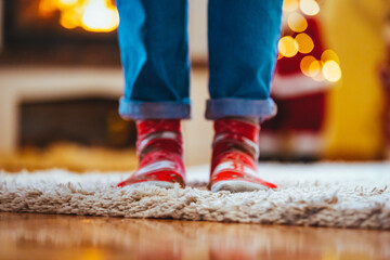 Feet of unrecognizable woman in woollen socks by the Christmas fireplace. Winter and Christmas holidays concept. Woman in Christmas mood. Young woman in her home in Christmas time