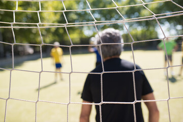 Back view of senior goalkeeper ready for match. Man with grey hair in gloves ready to catch ball,...