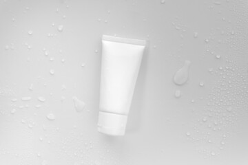  Top view above or flat lay mockup facial skincare white tube bottle product blank label with water...