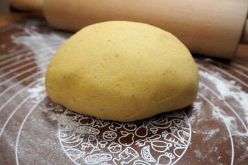 raw gluten-free and lactose-free shortbread dough lies on a brown silicone mat next to a wooden rocking chair. dough with rice and corn flour