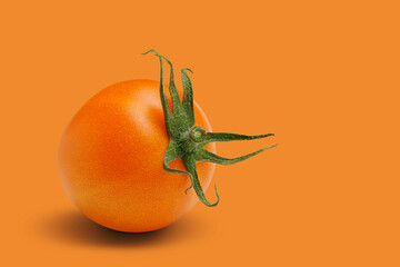 yellow or orange tomato lies on an orange background, concept