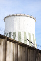 Large round white chimney industrial electric tower view building structure with barbed wire in foreground.
