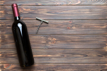 One Bottle of red wine with corkscrew on colored table. Flat lay, top view wth copy space