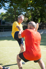 Obraz premium Determined senior men getting ready for match on sunny day. Men with grey hair in sport clothes warming up on sport field. Football, sport, leisure activities concept