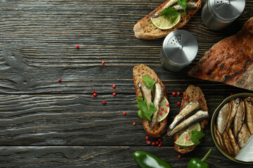 Concept of tasty snack with sandwiches with sprats on wooden background