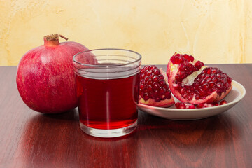Pomegranate fruits and pomegranate juice on a red wooden table